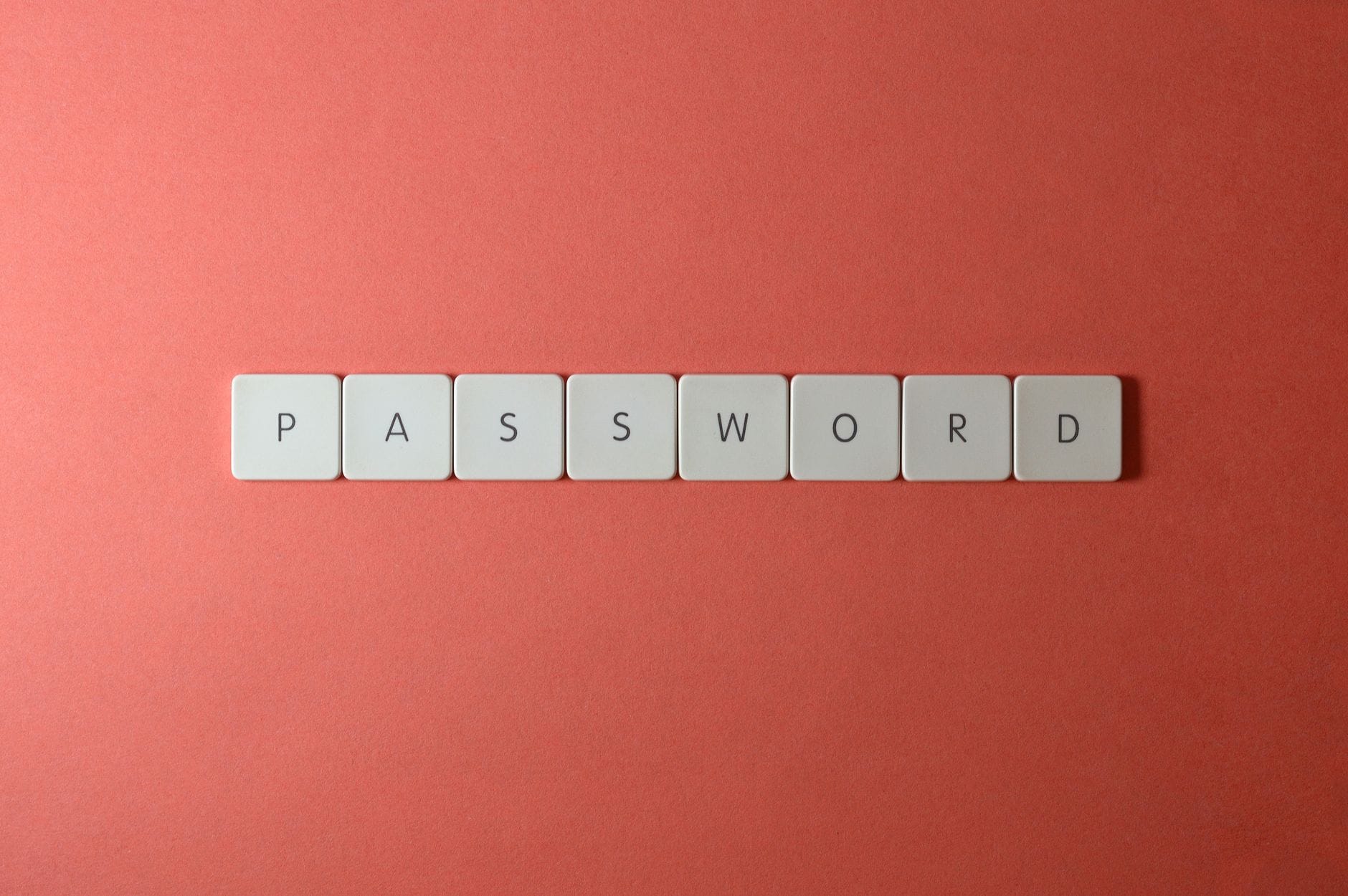Białe klawisze klawiatury układające się w napis PASSWORD na koralowym tle