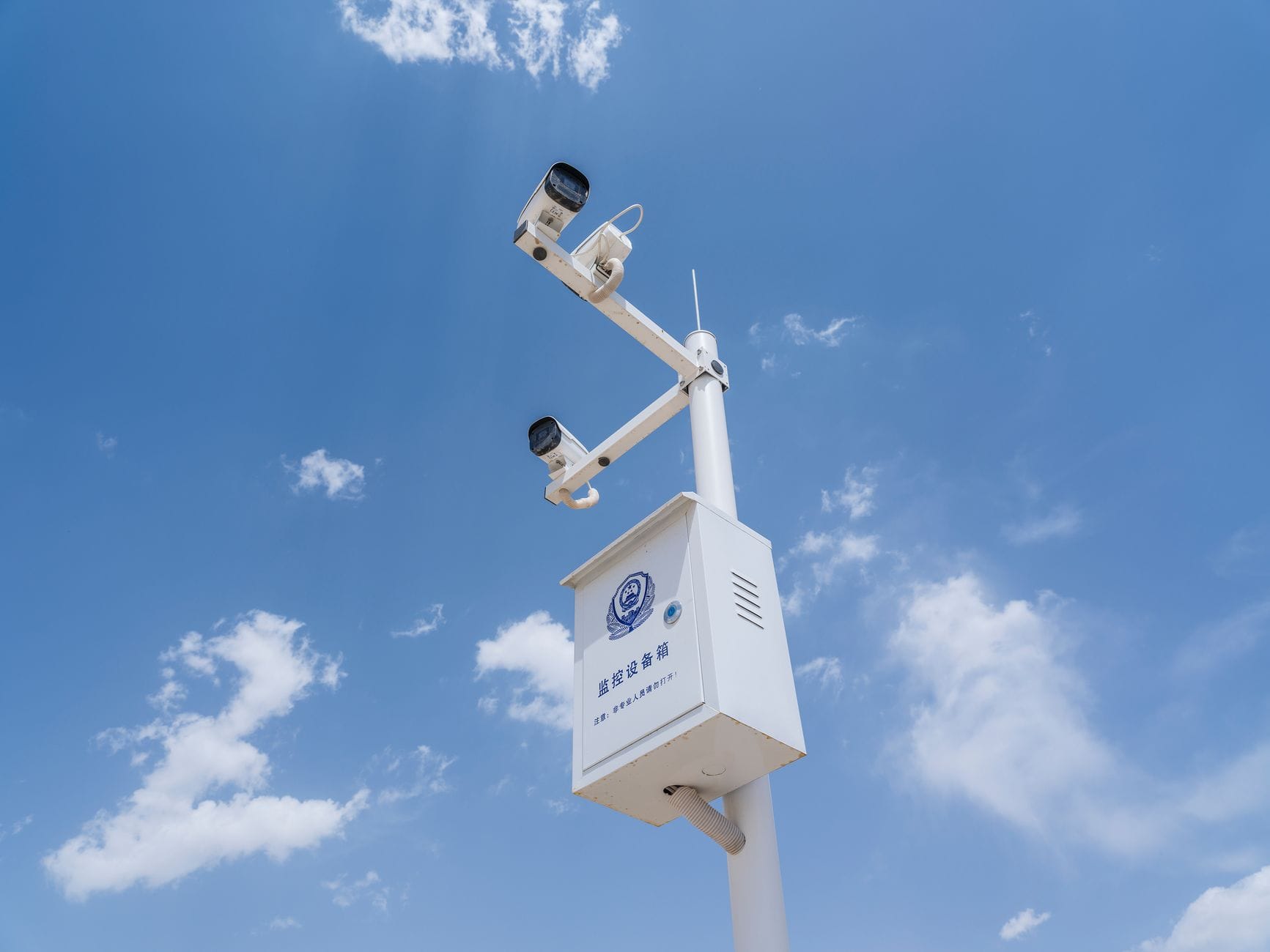 Kamery monitoringu na słupie na tle błękitnego nieba z chmurami