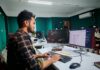 Programista pracujący nad kodem przy dwóch monitorach w biurze